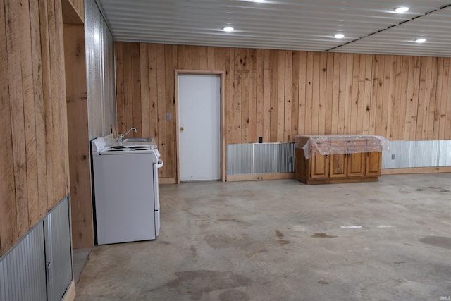 clothes washing area with washer / clothes dryer, wooden walls, and sink