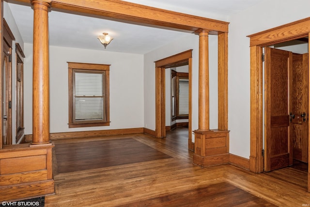 hall with ornate columns and dark wood-type flooring