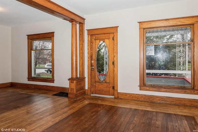 foyer entrance with ornate columns and dark hardwood / wood-style flooring