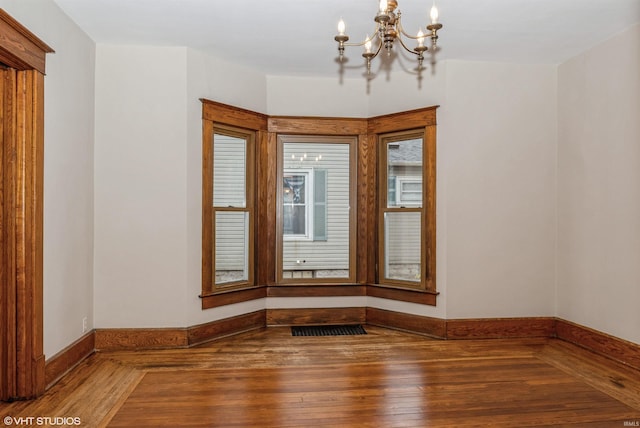 spare room featuring hardwood / wood-style floors and a chandelier