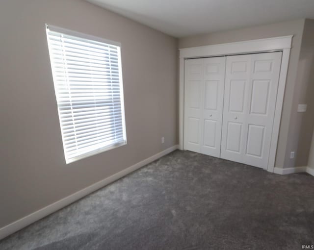 unfurnished bedroom featuring a closet and dark carpet