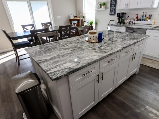 kitchen featuring white cabinets, decorative backsplash, dark hardwood / wood-style floors, and light stone countertops