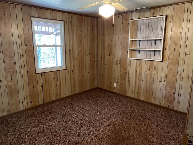 unfurnished room featuring carpet flooring, wood walls, and ceiling fan