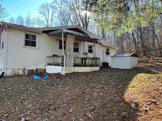 view of front facade with a porch, central AC unit, and a storage shed