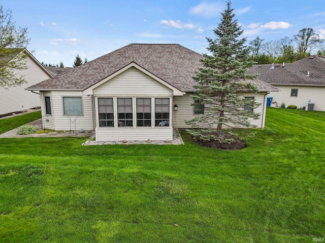 rear view of property featuring a lawn and central air condition unit