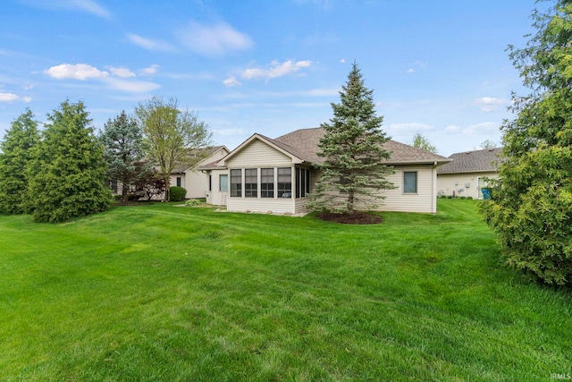 rear view of property featuring a sunroom and a yard