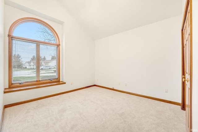 carpeted spare room with vaulted ceiling