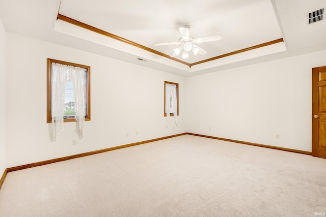 empty room with carpet, a tray ceiling, ceiling fan, and ornamental molding