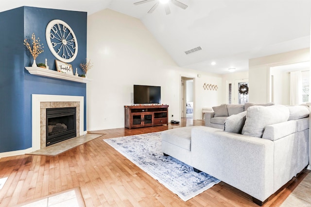 living room featuring a tiled fireplace, ceiling fan, hardwood / wood-style floors, and lofted ceiling