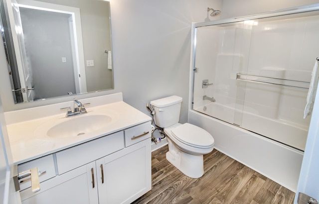 full bathroom with hardwood / wood-style floors, vanity, toilet, and enclosed tub / shower combo