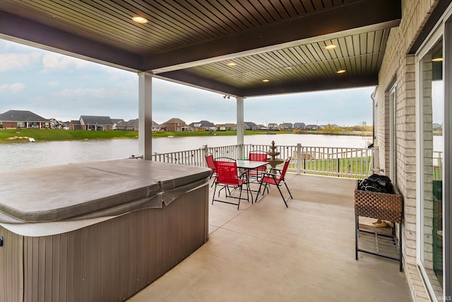 view of patio / terrace with a water view and a hot tub