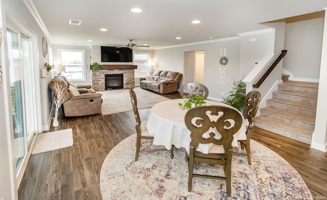 dining area featuring hardwood / wood-style floors, ceiling fan, ornamental molding, and a fireplace