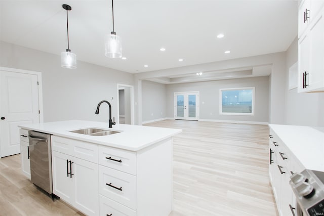 kitchen featuring sink, range, an island with sink, pendant lighting, and light wood-type flooring