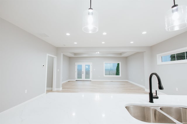 kitchen with sink, pendant lighting, french doors, and light hardwood / wood-style flooring