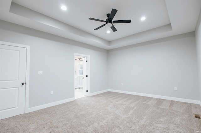 unfurnished room featuring carpet, ceiling fan, and a raised ceiling