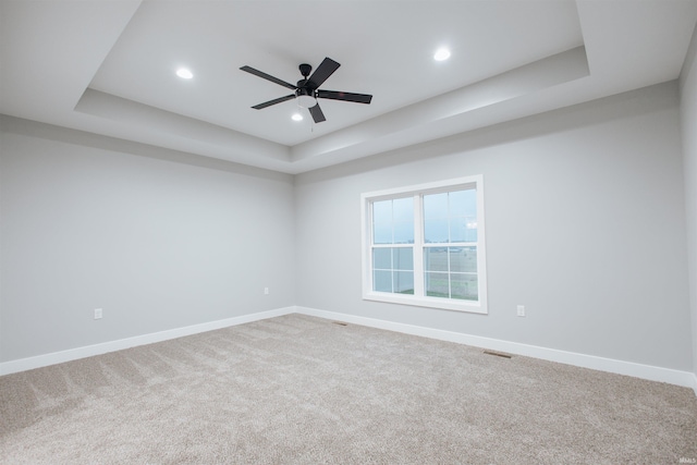 carpeted spare room featuring ceiling fan and a tray ceiling