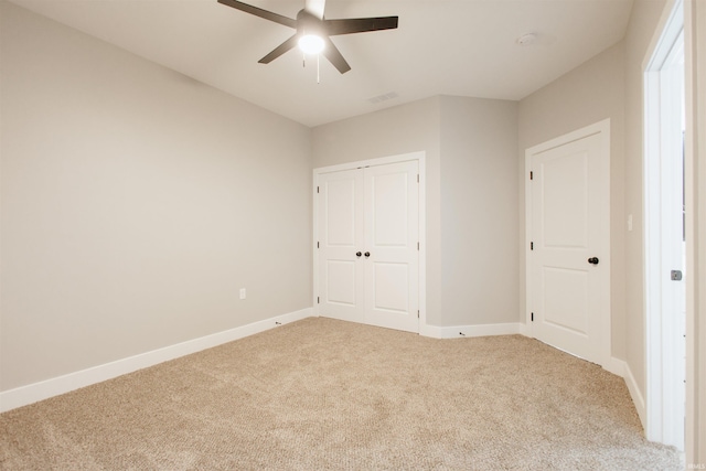 unfurnished bedroom featuring a closet, light colored carpet, and ceiling fan