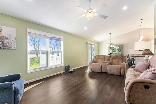 living room with a wealth of natural light, dark hardwood / wood-style flooring, ceiling fan, and vaulted ceiling