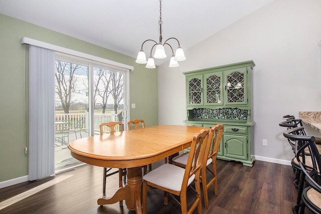 dining space with dark hardwood / wood-style floors, an inviting chandelier, and lofted ceiling