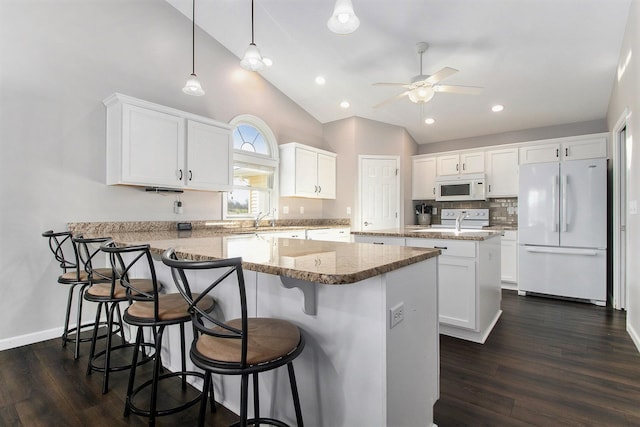 kitchen featuring white cabinets, white appliances, a center island, and dark hardwood / wood-style floors