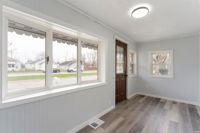 entrance foyer with ornamental molding, a healthy amount of sunlight, and wood-type flooring