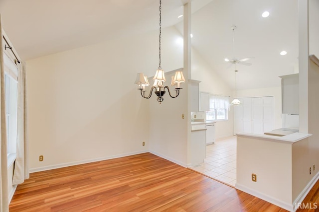 interior space featuring high vaulted ceiling, light hardwood / wood-style floors, and ceiling fan with notable chandelier