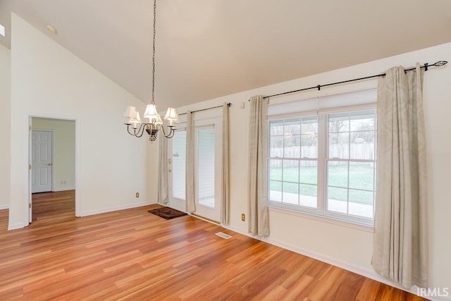 unfurnished dining area with a notable chandelier, wood-type flooring, and high vaulted ceiling