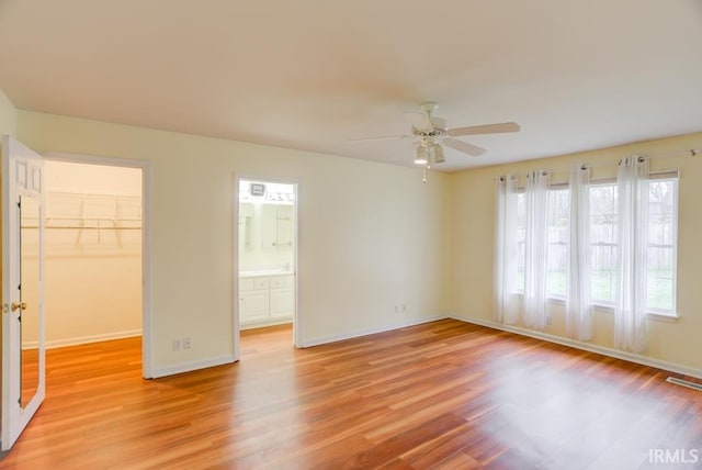 unfurnished bedroom with ceiling fan, light hardwood / wood-style floors, a walk in closet, and a closet