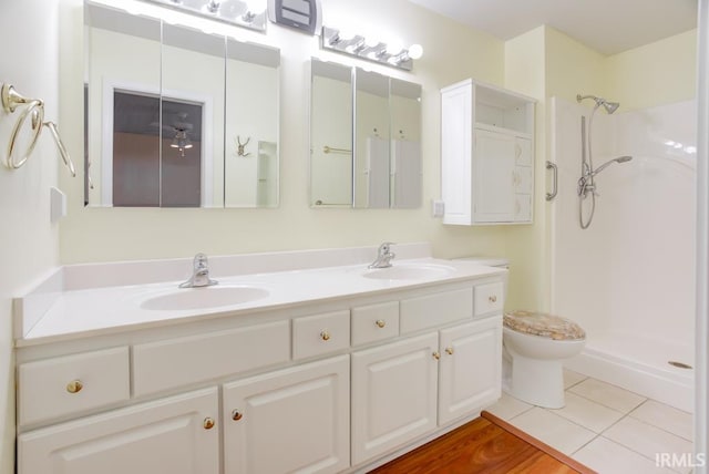 bathroom featuring tile patterned flooring, vanity, toilet, and walk in shower