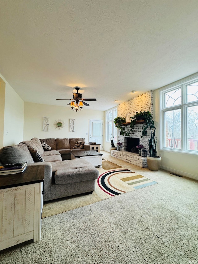 carpeted living room with ceiling fan, a textured ceiling, and a brick fireplace