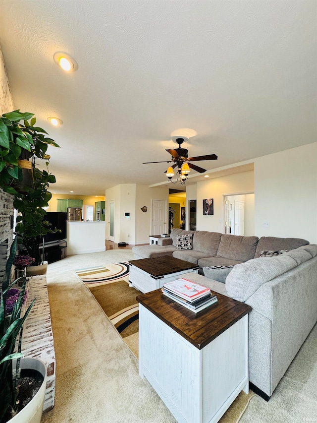 carpeted living room with ceiling fan and a textured ceiling