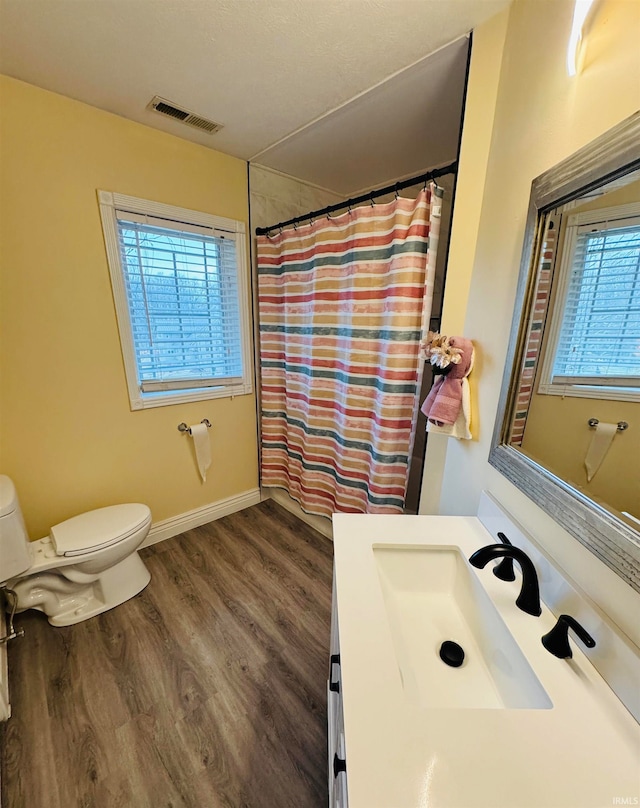 bathroom with plenty of natural light, vanity, hardwood / wood-style floors, and toilet