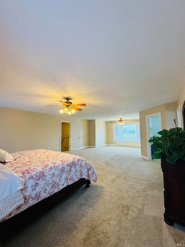 bedroom featuring a textured ceiling, light colored carpet, and ceiling fan