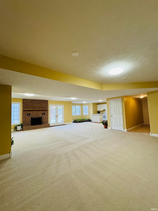 basement with carpet flooring, a textured ceiling, a brick fireplace, and plenty of natural light