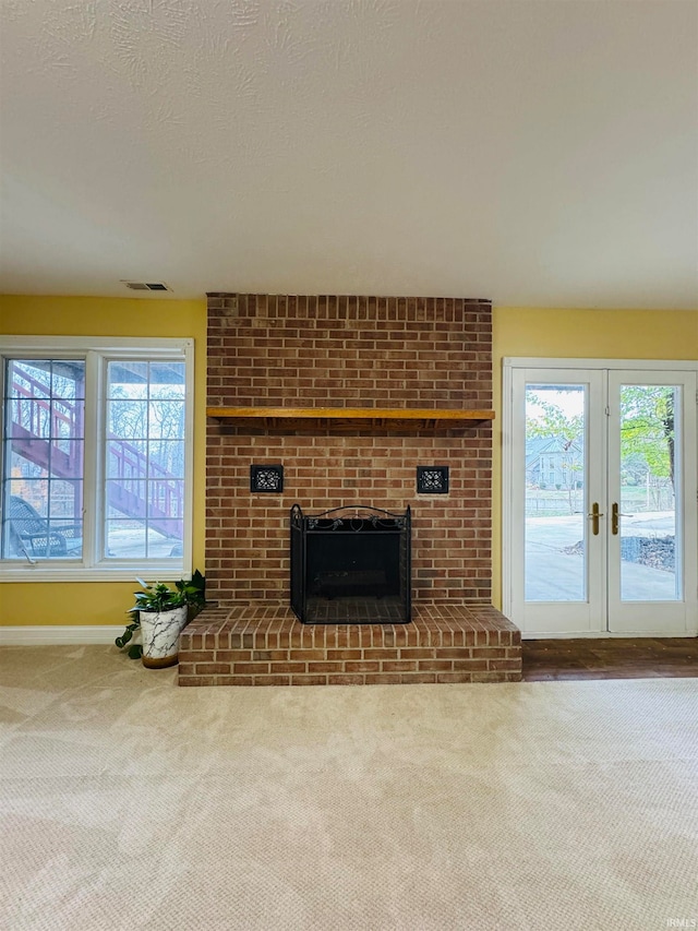 unfurnished living room with a fireplace, carpet floors, and plenty of natural light