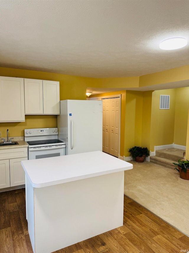 kitchen with a textured ceiling, white appliances, white cabinetry, and dark hardwood / wood-style flooring