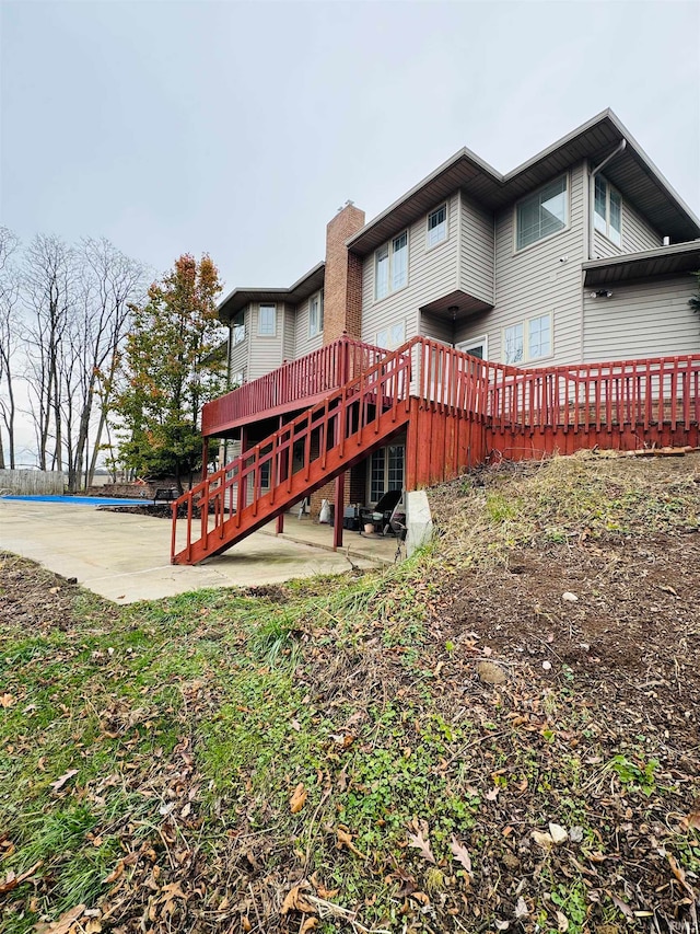 back of property featuring a patio and a wooden deck