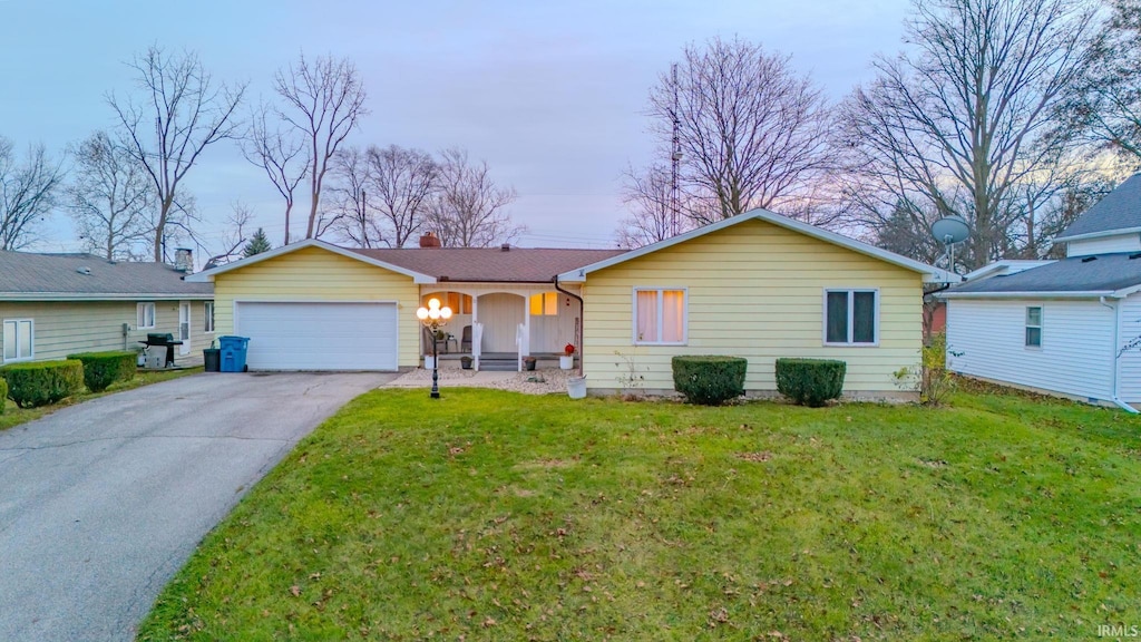 ranch-style house featuring a garage and a front lawn