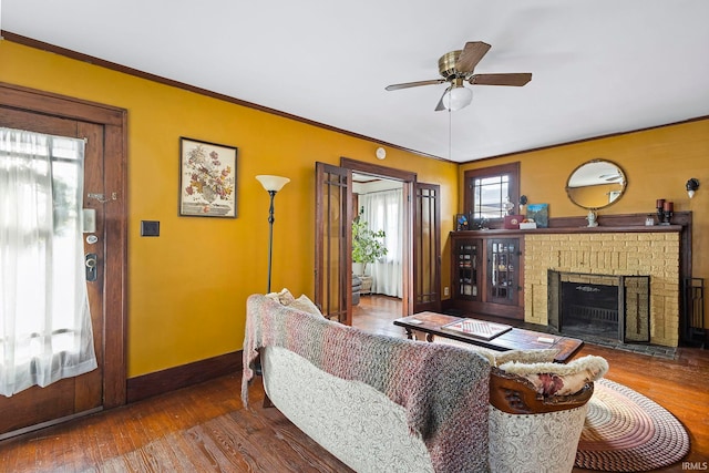 living room with hardwood / wood-style floors, ceiling fan, ornamental molding, and a fireplace