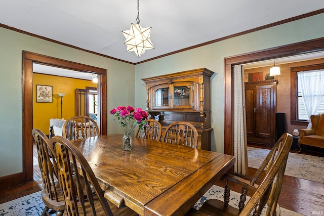 dining space featuring wood-type flooring, ornamental molding, and a notable chandelier