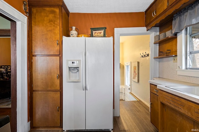 kitchen with hardwood / wood-style floors, white refrigerator with ice dispenser, and a textured ceiling