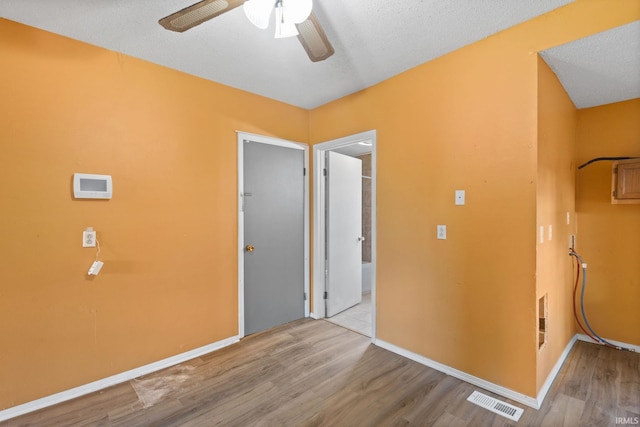 unfurnished room with ceiling fan, a textured ceiling, and light wood-type flooring