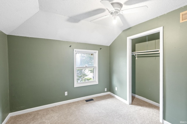 unfurnished bedroom with a closet, vaulted ceiling, ceiling fan, and light colored carpet