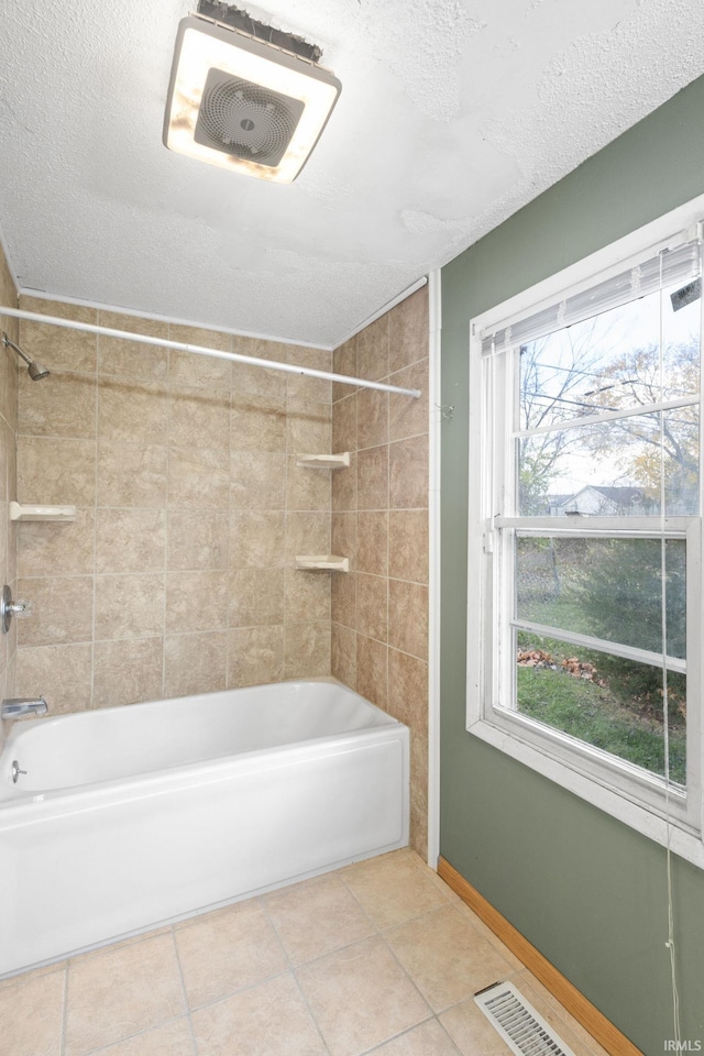 bathroom with tile patterned floors, plenty of natural light, tiled shower / bath combo, and a textured ceiling