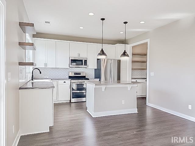 kitchen with pendant lighting, dark wood-type flooring, white cabinets, and stainless steel appliances