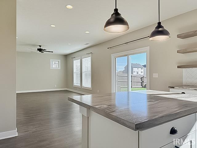 kitchen featuring tasteful backsplash, ceiling fan, dark wood-type flooring, decorative light fixtures, and white cabinets