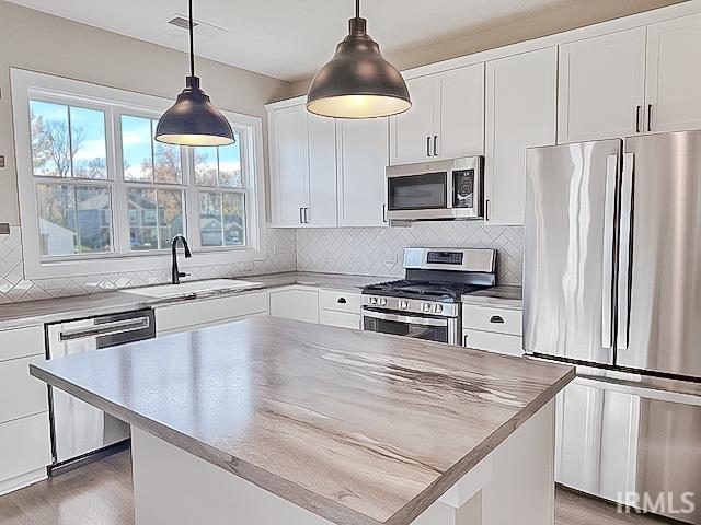 kitchen featuring white cabinets, appliances with stainless steel finishes, pendant lighting, and sink