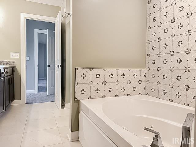 bathroom with tile patterned flooring, vanity, tile walls, and a bathing tub