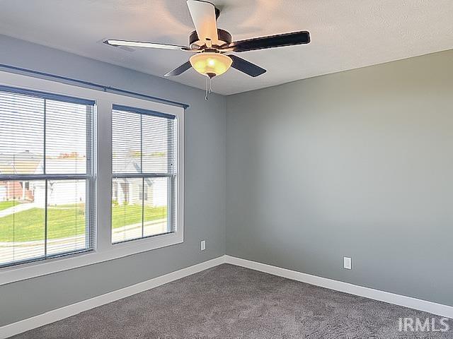 carpeted spare room featuring a textured ceiling and ceiling fan