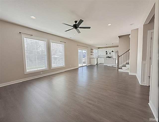 unfurnished living room with dark hardwood / wood-style flooring, a wealth of natural light, and ceiling fan